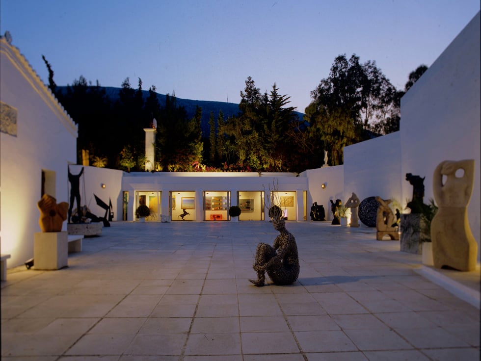 Sculptures in the illuminated courtyard of Vorres Museum at dusk